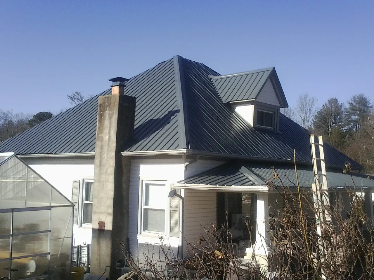 Dark blue standing seam metal roof on a white farmhouse with dormer — Slate & Tile Roof Repair by Roofing Brothers in Bellows Falls