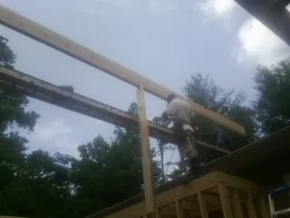 Carpenter setting a ridge beam over a new addition frame — Ice Dam Removal by Roofing Brothers in Bellows Falls