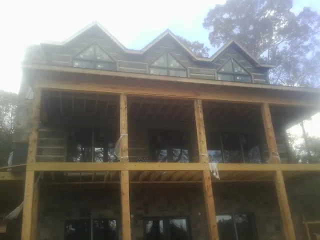 Dormers and porch framing on a large log home under construction — Roof Coating work by our crew in Bellows Falls