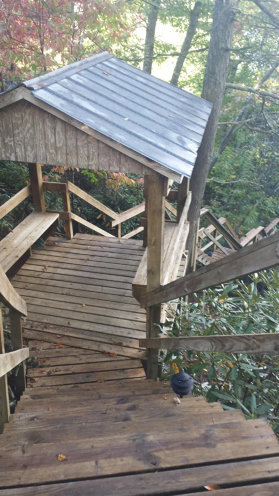Metal roofed shelter over wooden steps on a wooded walkway — Skylight Repair & Installation work by our crew in Bellows Falls